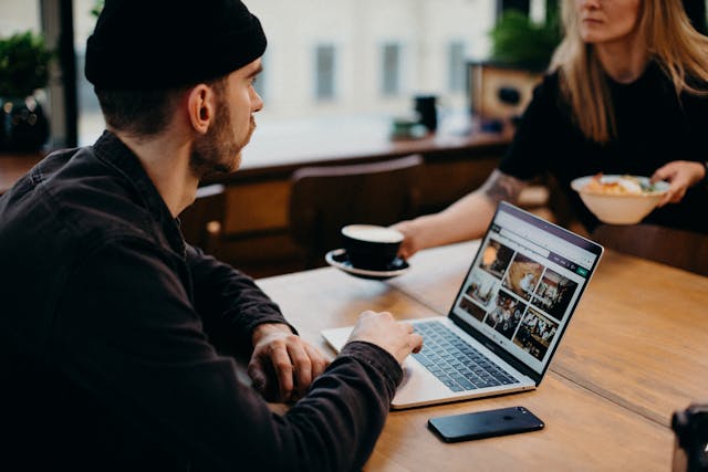 A man talking to a woman while using his computer